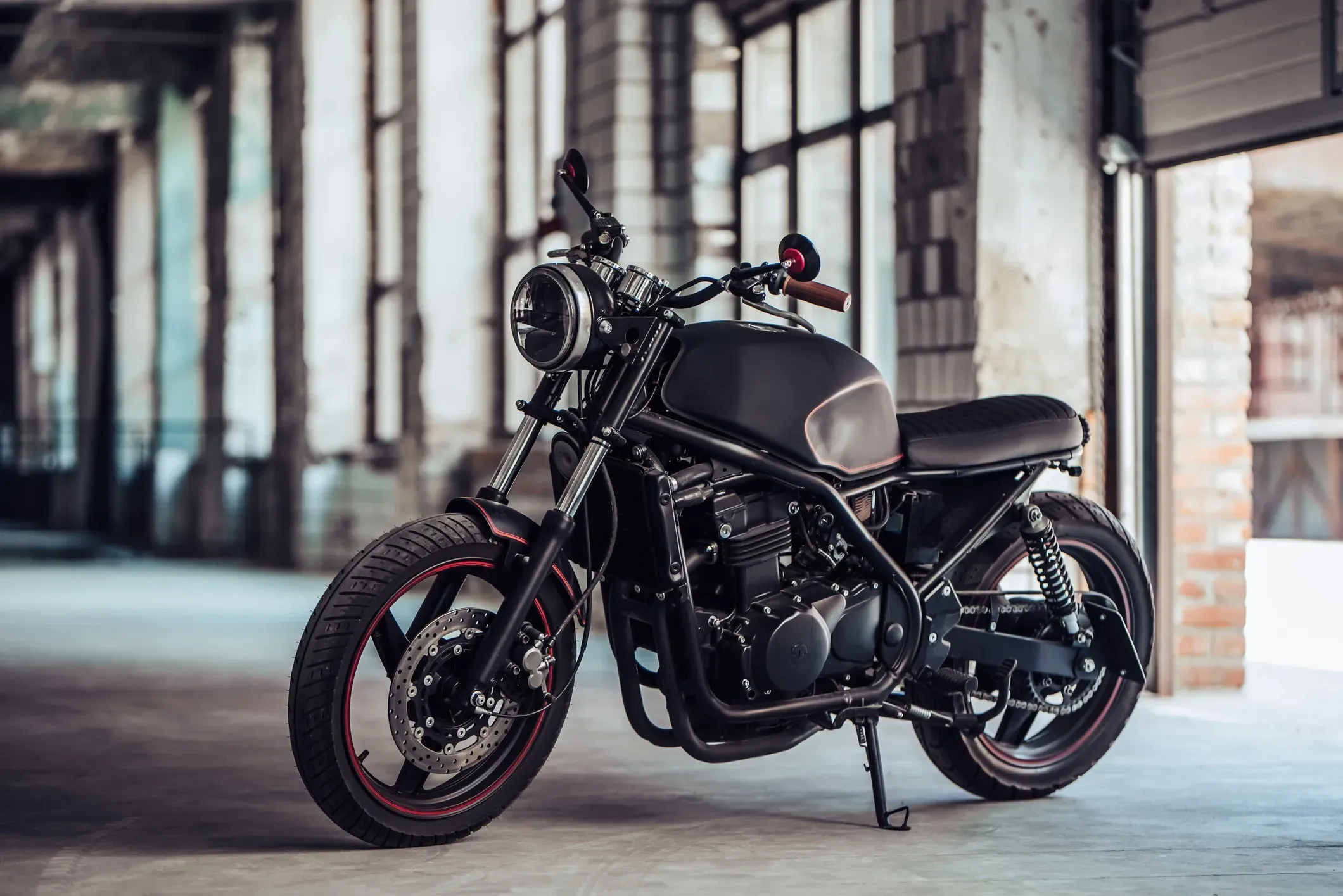 A black cruiser motorcycle in a garage full of windows.  
